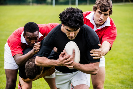 Rugby players tackling during game at the parkの写真素材