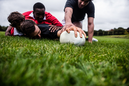 Rugby players tackling during game at the parkの写真素材