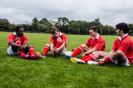 Rugby players sitting on grass before match at the parkの写真素材