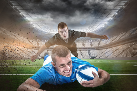Confident rugby player lying in front with ball against rugby stadiumの写真素材