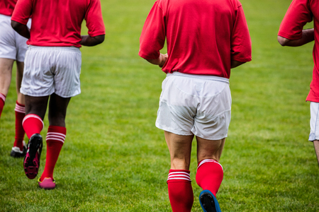 Rugby players jogging with ball at the parkの写真素材