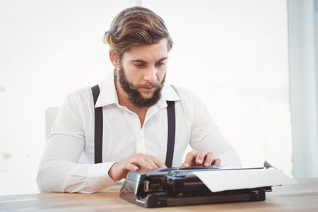 Hipster working on typewriter at desk in officeの写真素材
