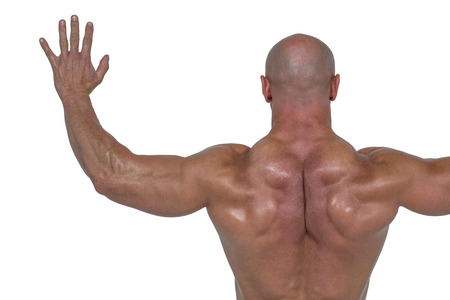 Rear view of bodybuilder with arms outstretched against white backgroundの写真素材