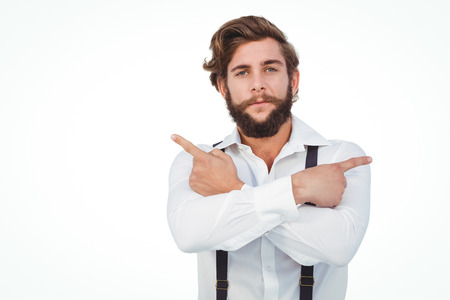 Portrait of confident hipster pointing sideways with arms crossed against white background