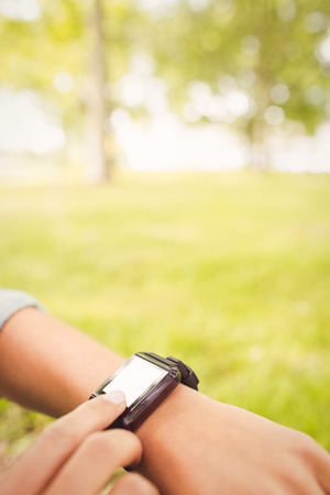 Cropped hands touching smart watch while sitting in parkの写真素材