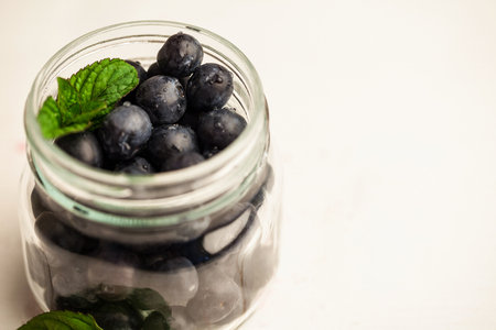 Glass jar of fresh blueberries on wooden tableの写真素材