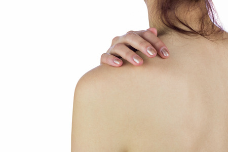 Rear view of topless woman touching back against white backgroundの写真素材