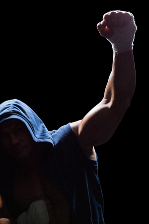 Winner athlete with arms raised against black backgroundの写真素材