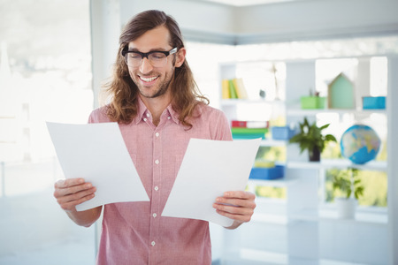 Happy hipster looking at documents in officeの写真素材