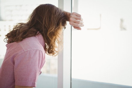 Side view of man looking through window in officeの写真素材