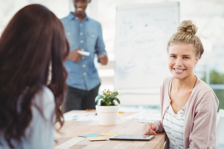 Portrait of smiling woman with coworker at desk in officeの写真素材