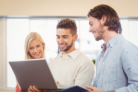 Happy business people using laptop in creative office