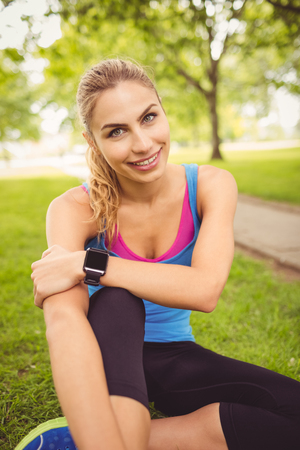 Portrait of happy woman with legs crossed while sitting on grass in parkの写真素材