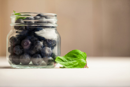 Glass jar of fresh blueberries on wooden tableの写真素材