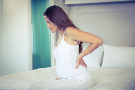 Pregnant woman sitting with back pain on bedの写真素材