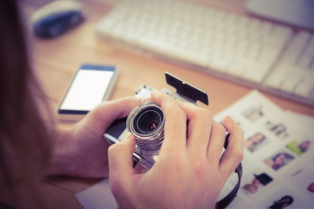 Cropped image of man adjusting camera lens at desk in office