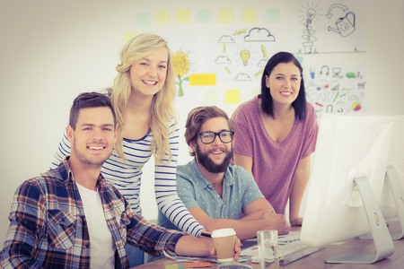 Portrait of happy business professionals working at computer desk in creative office