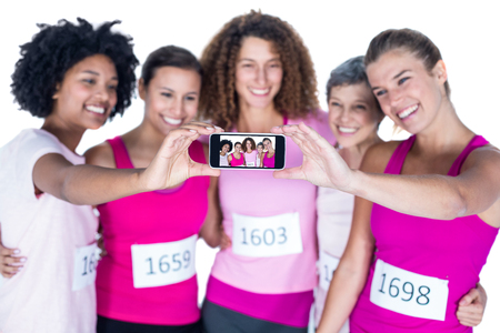 Smiling athletes taking self portrait with smartphone while standing against white backgroundの写真素材