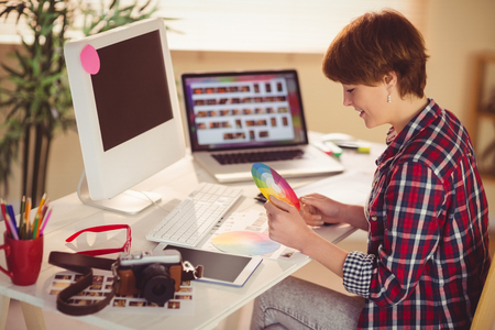 Casual female designer working with digitizer and colour chart in officeの写真素材