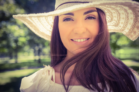 Portrait of smiling woman in sun hat while standing in parkの写真素材