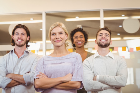 Smililng young business creative team looking away with arms crossed in officeの写真素材