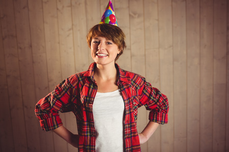 Pretty woman with hands on hips posing on wooden planks backgroundの写真素材