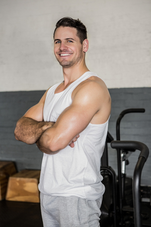 Portrait of a smiling muscular man with arms crossed at the gymの写真素材
