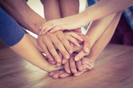 Business team putting their hands together at desk in office