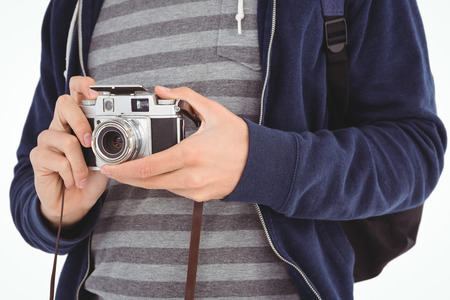 Mid section of man with camera standing against white backgroundの写真素材