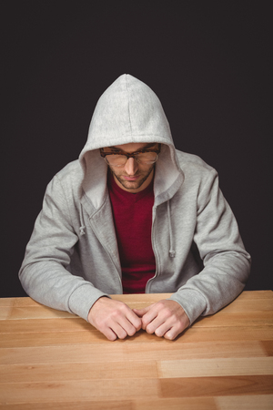 High angle view of man with hooded shirt sitting at desk in officeの写真素材