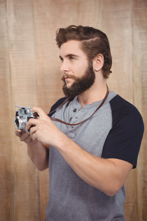 Hipster using digital camera against wooden wallの写真素材