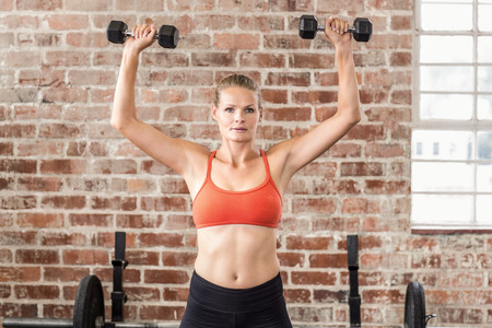 Fit woman exercising with dumbbells in the gymの写真素材