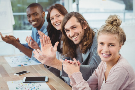 High angle portrait of smiling business people clapping at desk in office