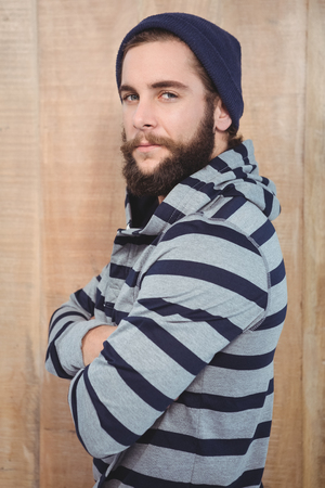 Portrait of confident hipster with hooded shirt against wooden wallの写真素材