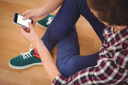 Cropped image of hipster using smartphone while sitting in officeの写真素材