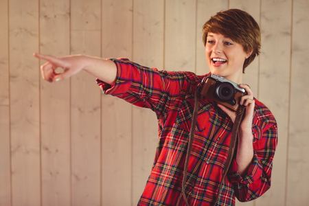 Attractive young woman photographing with camera on wooden planks backgroundの写真素材