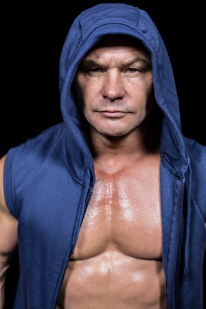 Portrait of muscular man in blue hood against black backgroundの写真素材