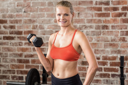 Fit woman exercising with dumbbell in the gym