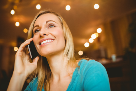 Close-up of happy young woman using mobile phone in cafeの写真素材