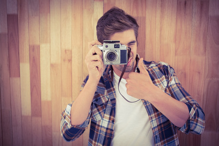 Hipster showing thumbs up while photographing against wooden wallの写真素材