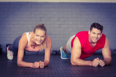 Fit smiling couple planking together in gym in crossfit gymの写真素材
