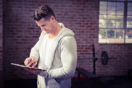 Muscular man holding clipboard at the gymの写真素材