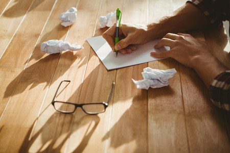 Cropped image of hipster writing on paper at desk in office