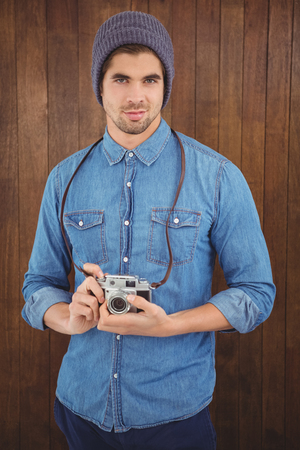 Portrait of confident  hipster using camera against wooden wallの写真素材