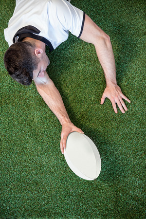 High angle view of man holding rugby ball over the grassの写真素材