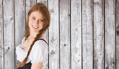 Oktoberfest girl smiling at camera against digitally generated grey wooden planksの写真素材