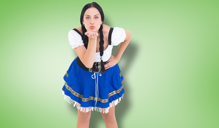 Pretty oktoberfest girl blowing a kiss against green vignetteの写真素材