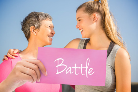 The word battle and hand holding card against sporty mother and daughter smiling at each otherの写真素材