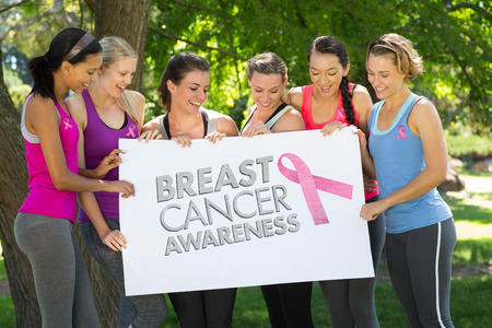 Breast cancer awareness message against fitness group holding poster in parkの写真素材