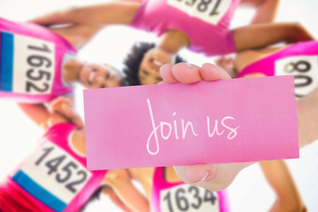 The word join us and young woman holding blank card against five smiling runners supporting breast cancer marathonの写真素材